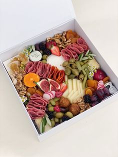 a white box filled with assorted meats and cheese on top of a table