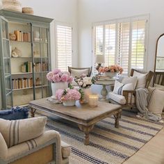 a living room filled with lots of furniture and flowers on top of a coffee table