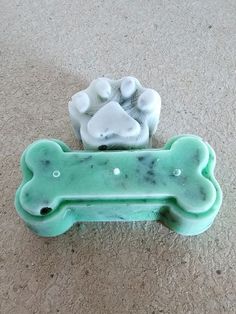 two bone shaped soap dishes sitting on the floor next to each other in front of a dog's paw