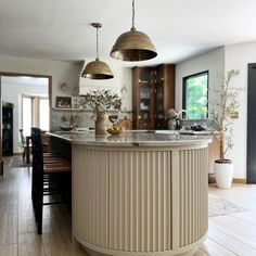 a kitchen with two pendant lights hanging from the ceiling and an island in the middle