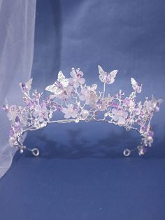 a tiara with pink flowers and butterflies on the headpiece is shown against a blue background