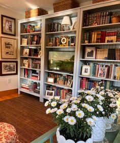 a living room filled with lots of books and flowers