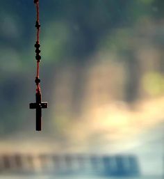 a black cross hanging from a chain on a window sill in front of a blurry background