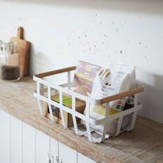 a white basket filled with food sitting on top of a wooden shelf next to a counter