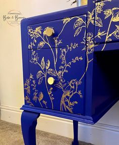 a blue and gold painted dresser with flowers on it