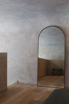 a mirror sitting on top of a wooden floor next to a bed in a room