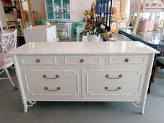 a white dresser with gold handles in a store