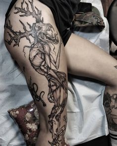 a woman's leg with tattoos on it and an image of a man holding a cross