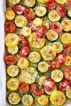 a casserole dish with tomatoes, zucchini and parmesan cheese