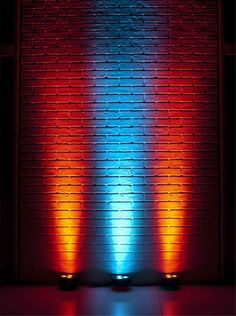 the light is shining brightly in front of a brick wall with red and blue lights