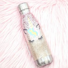 the unicorn water bottle is sitting on a pink fur covered surface with it's lid open