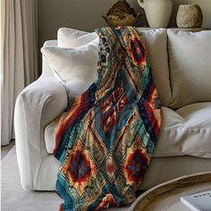 a couch with a blanket on top of it next to a coffee table and vase