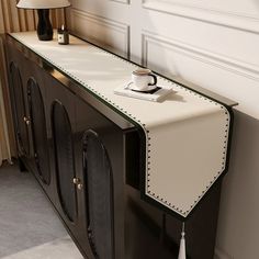 a black and white sideboard with a coffee cup on it next to a lamp