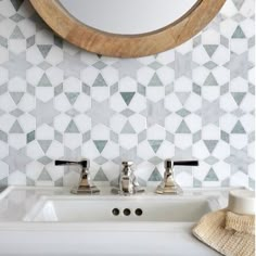 a white sink sitting under a round mirror