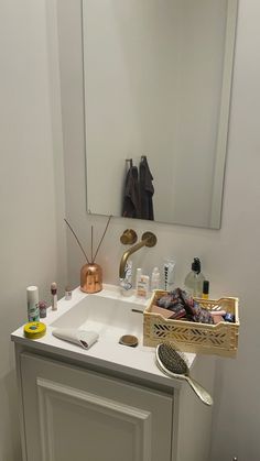 a bathroom with a sink, mirror and various items on the counter top in front of it