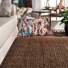 a living room filled with lots of furniture and pillows on top of a brown rug