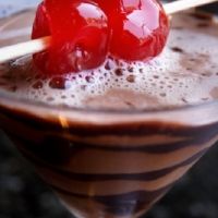 two cherries sit on top of a chocolate drink