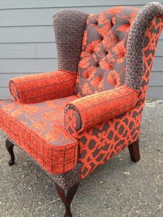 an orange and grey chair sitting on top of a gravel ground next to a building