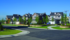 a street with lots of houses and trees in the front, along with grass on both sides