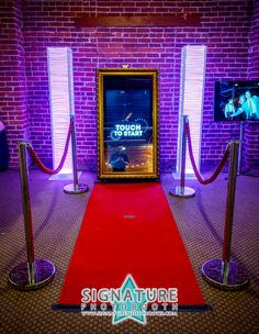 a red carpeted area with metal barriers and two televisions on the wall behind it