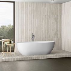 a large white bathtub sitting next to a window in a room with wood flooring