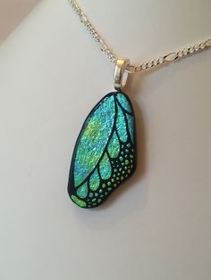 a necklace with a green and blue butterfly wing on it