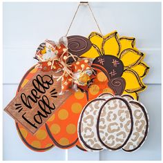 a door hanger decorated with pumpkins, sunflowers and fall tags that say happy fall