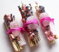 three wooden sticks with flowers and soap wrapped in pink ribbon on top of each other