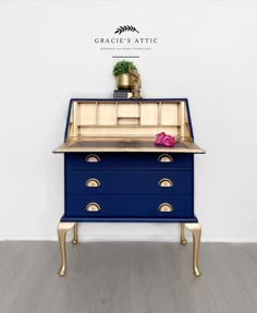 a blue dresser with gold handles and drawers on it's sides, in front of a white wall