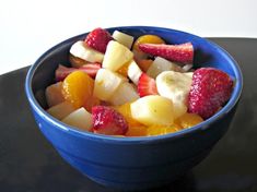 a blue bowl filled with fruit on top of a table