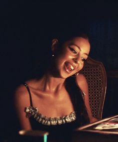 a woman sitting at a table with a laptop in front of her and smiling for the camera