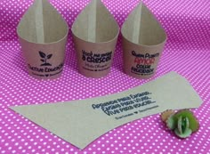 three paper cups sitting on top of a table next to a piece of broccoli