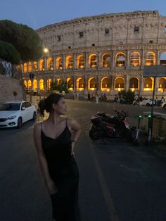 a woman standing in front of the colossion at night with her hand on her hip