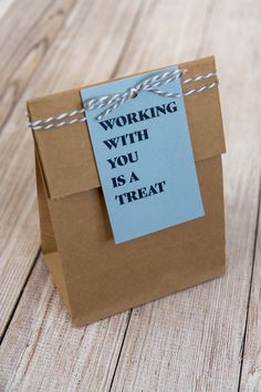 a brown paper bag with a note attached to it that says working with you is a treat