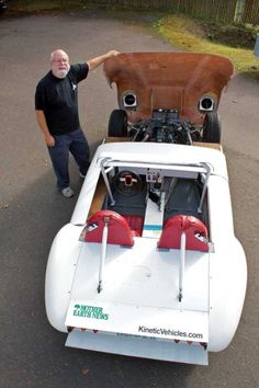 a man standing next to a white car with two engines on it's hood