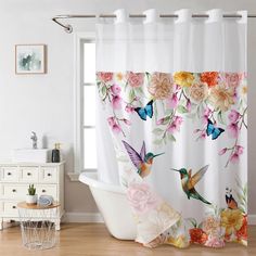 a bath tub sitting next to a window covered in curtains with flowers and hummingbirds