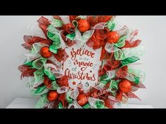 a christmas wreath with red and green decorations on it that says believe in the magic of christmas