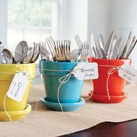 four pots with forks and spoons in them sitting on a table next to each other