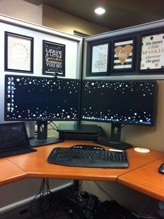 two computer monitors sitting on top of a wooden desk