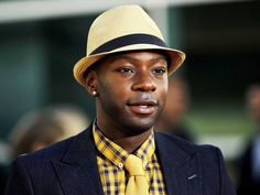 a man in a suit and tie wearing a yellow hat with black band around the brim