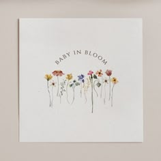 a card with the words baby in bloom written on it, surrounded by wildflowers