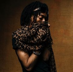 a man with dreadlocks is wrapped in a leopard print scarf