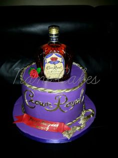 a purple cake with a bottle of liquor on top and red ribbon around the bottom