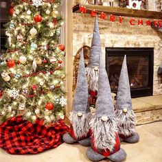 three gnomes sitting next to a christmas tree in front of a fire place and fireplace