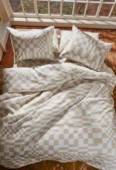 an unmade bed with checkered sheets and pillows