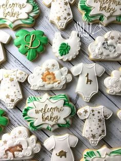 baby shower cookies decorated with green and white icing are arranged on a wooden table