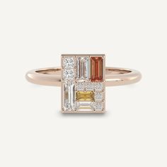 a gold ring with an orange and white baguette in the center, surrounded by diamonds