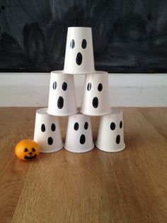 a stack of white cups sitting on top of a wooden table next to an orange