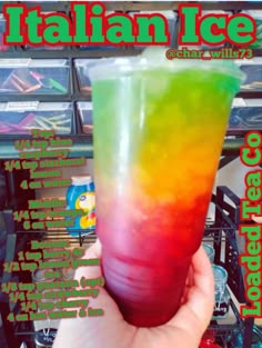 a hand holding up a colorful drink in front of a pile of plastic containers and boxes