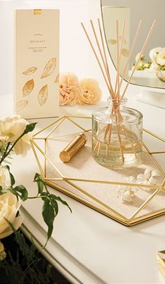 a table topped with candles and flowers next to a card on top of a mirror